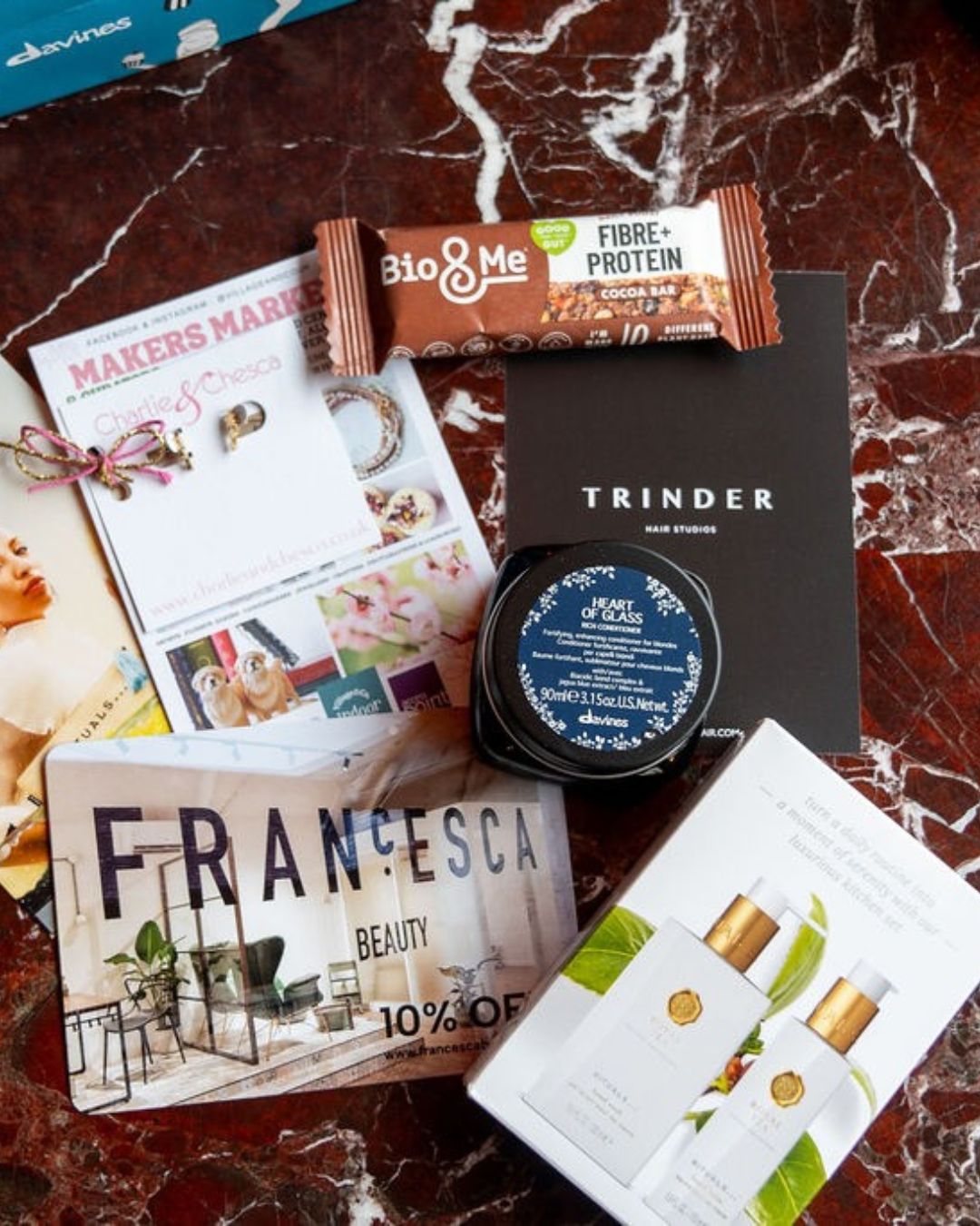 Goody bag gifts and vouchers from local businesses, laid out on a marble table