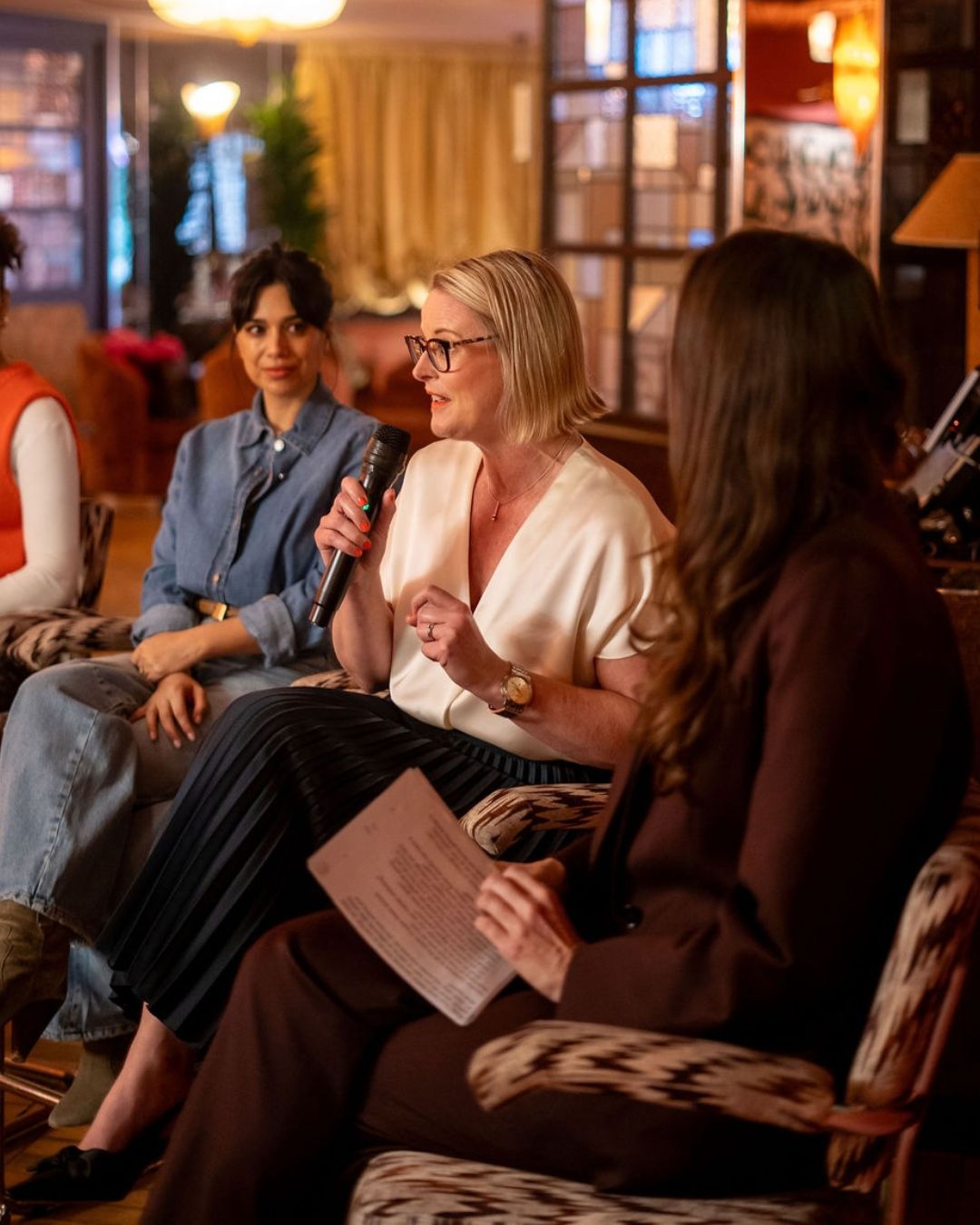 Panel speaker with a microphone, seated beside fellow panellists