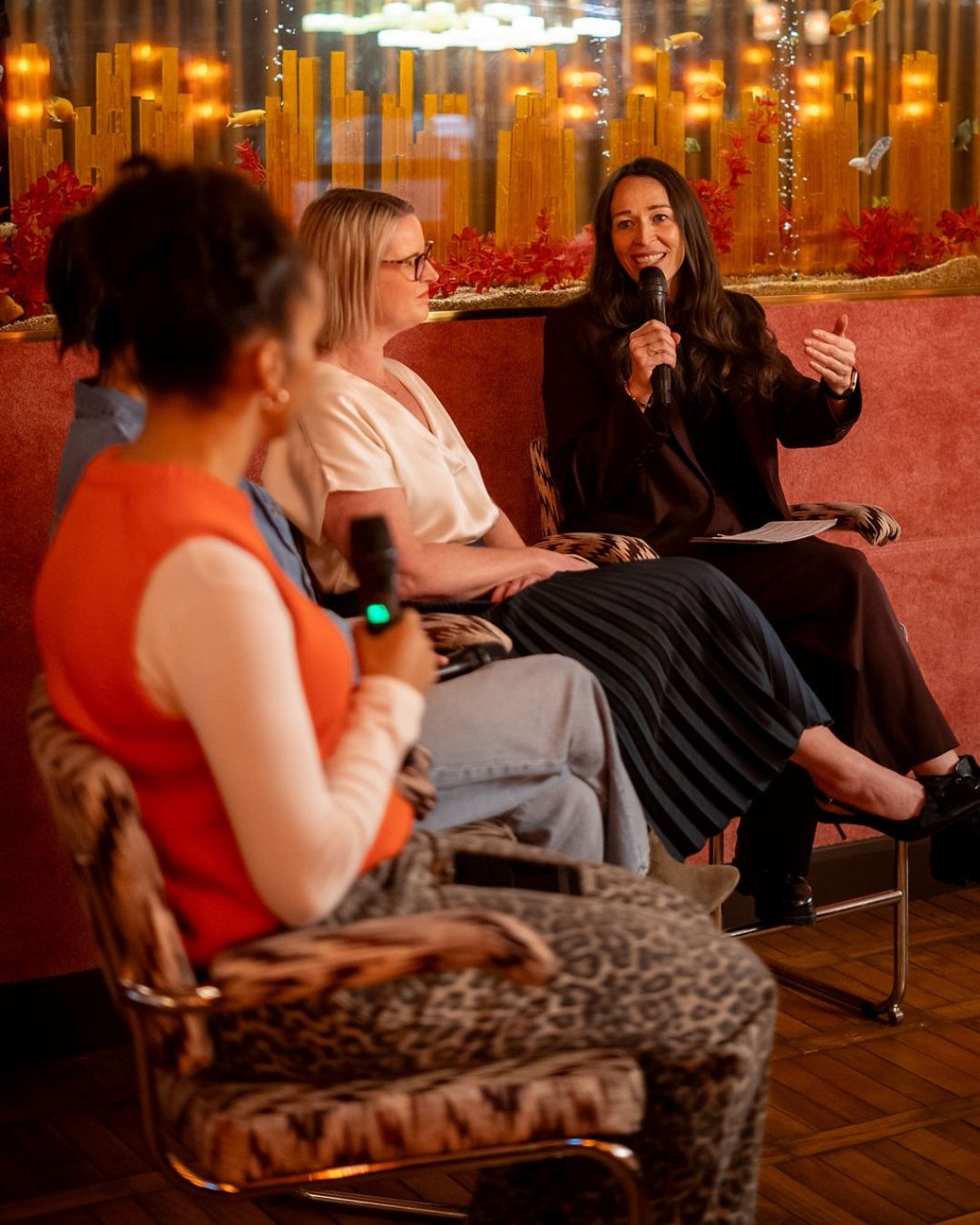 The panel in conversation in front of a warmly lit backdrop